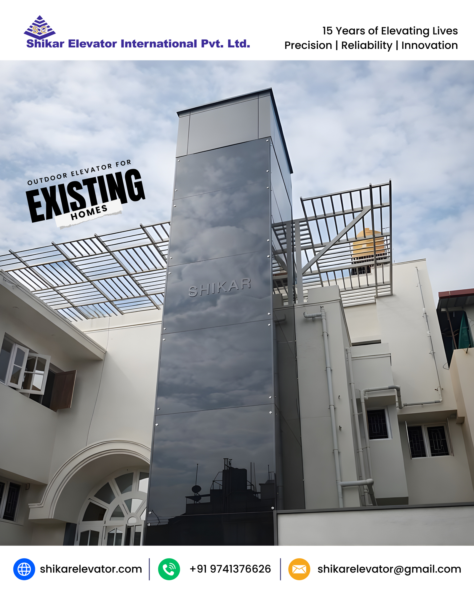 Outdoor Elevator - A glossy black outdoor elevator tower rising elegantly beside a traditional home, perfectly complementing the white walls, arched windows, and sloped roof – this real installation showcases Shikar's German‑engineered outdoor elevators transforming existing buildings with minimal disruption. The customer was thrilled with how this retrofit solution enhanced accessibility, property value, and architectural harmony without major structural changes. Ideal for older homes, apartments, and villas, Shikar outdoor elevators deliver luxury convenience through proven German precision technology.